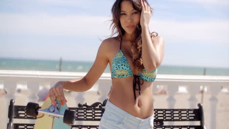 Young-woman-with-her-skateboard-at-the-beach