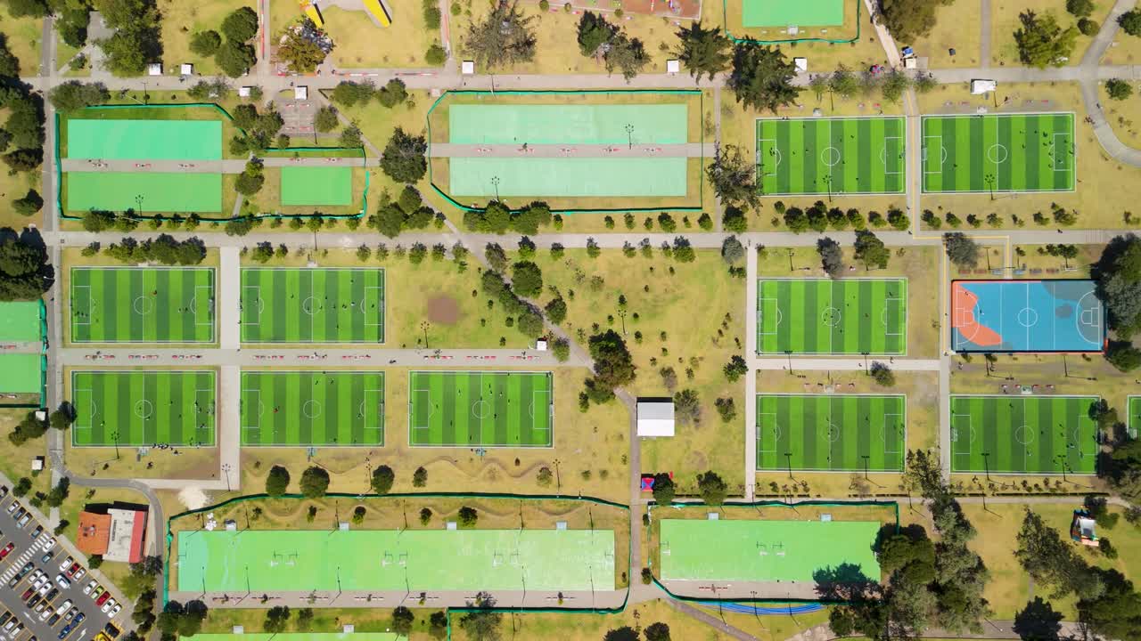 Top-down aerial flyover of Parque La Carolina Quito revealing dense grid of green futsal fields and sports courts