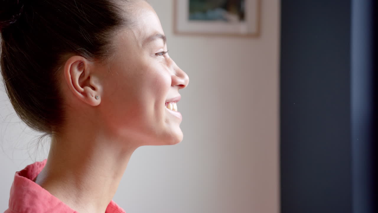 행복한 인종 십대 소녀가 집에서 창밖을 바라보고 미소 짓고, 공간을 복사하고, 느린 동작을 하고