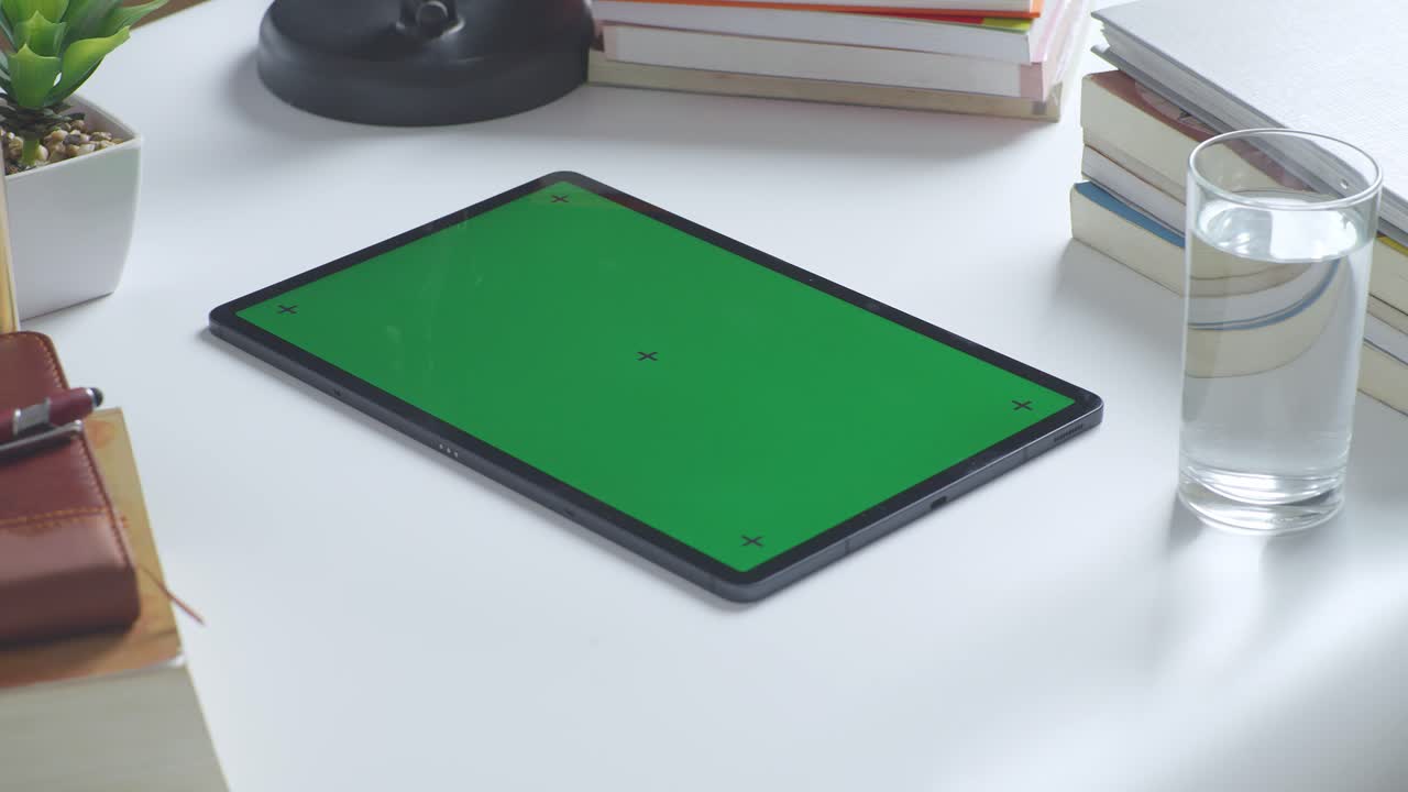 책과 함께 책상 위에 초록색 화면을 가진 태블릿