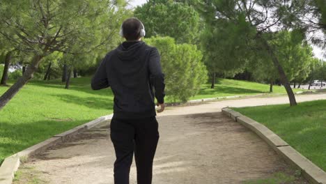 Running-man-in-white-helmets-and-white-sneakers-with-his-back-to-the-camera