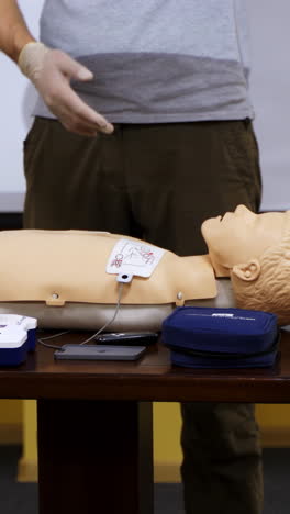 emergency first aid cpr procedure. demonstrating chest compressions on cpr doll in the class. vertical video