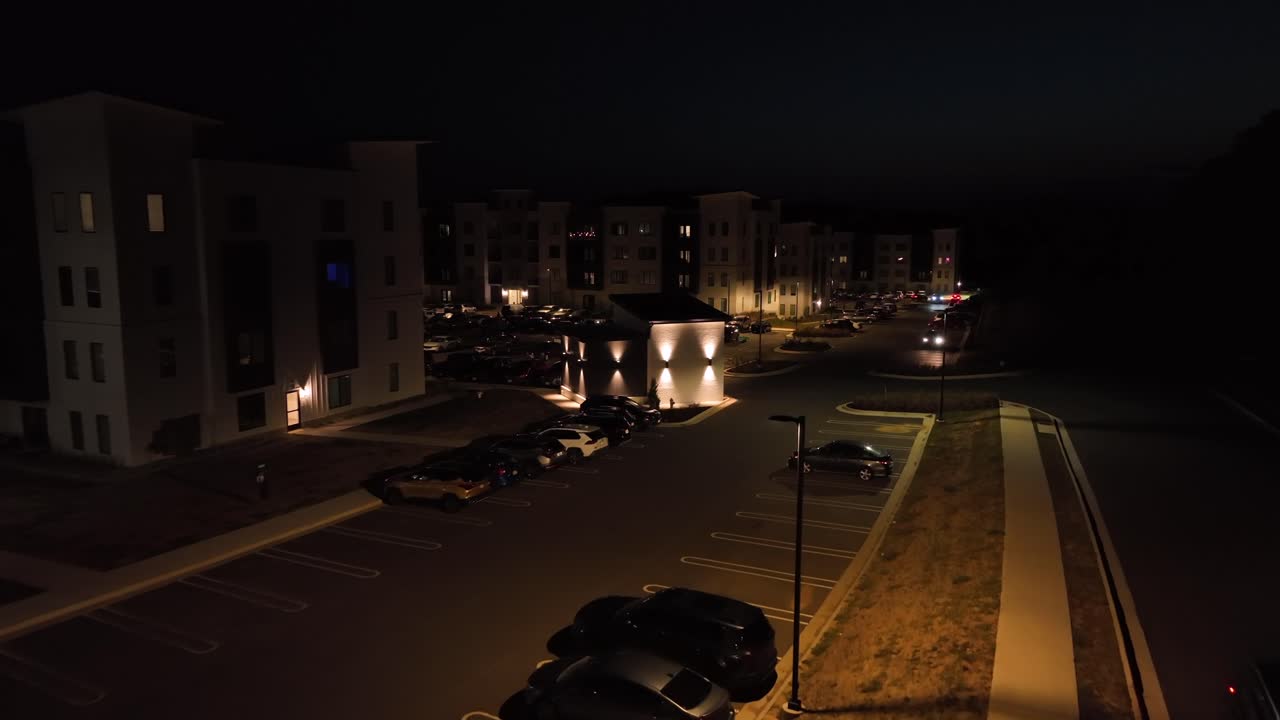 Luxury suburb neighborhood with apartments multi family units at night. Driving car leaving parking area. Lighting lantern and Home in usa. Peaceful Nightscape scene