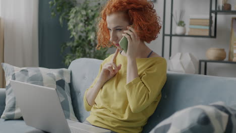 woman talking on phone and using laptop at home
