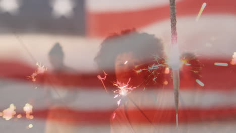 animation of american flag waving over woman holding sparklers on beach