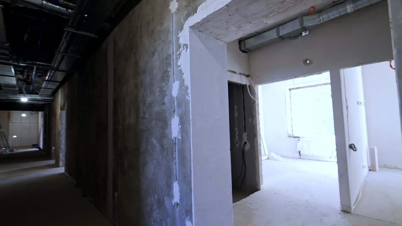Inside the building being constructed. View on the bare walls, door holes and pipes on the ceiling.