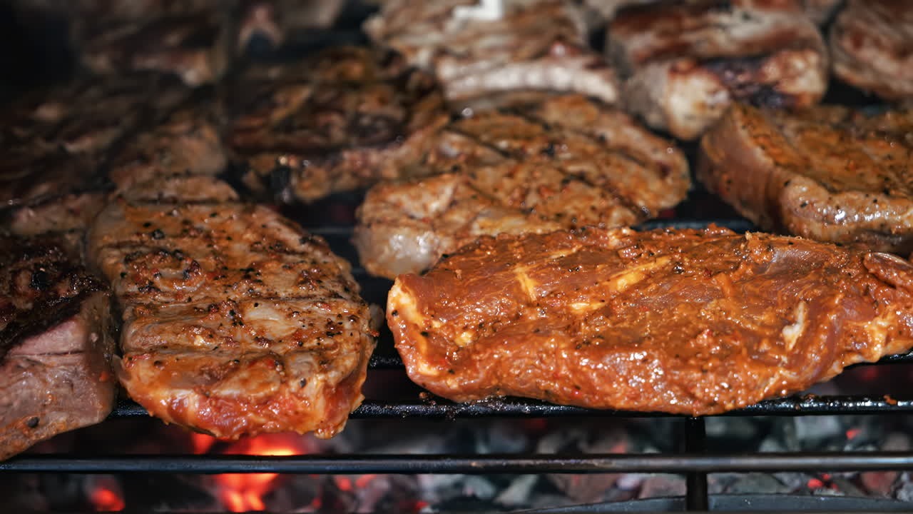 Roasting juicy meat steak with spices and herbs in burning charcoals fire on barbeque grid. Flames and smoke. Close up
