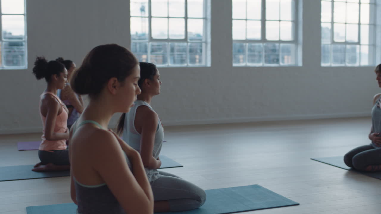 instructor de clase de yoga liderando meditación de atención plena enseñando a un grupo de mujeres sanas ejercicio de respiración disfrutando de la práctica espiritual en el gimnasio al amanecer