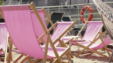 Pink-folding-sun-loungers-on-the-sandy-beach,-waiting-for-visitors-on-hot-days