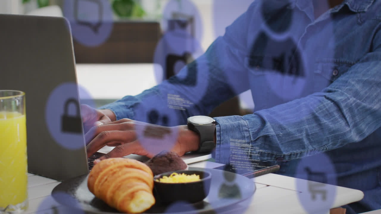 múltiples iconos digitales flotando contra un hombre afroamericano usando una computadora portátil