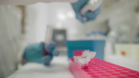 Close-up-of-a-laboratory-assistants-hand-of-a-woman-in-a-protective-suit-doing-research-with-blood-samples-of-a-virus-infected