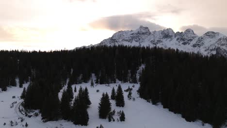 Ascending-aerial-reveal-of-rugged-snowy-Italian-alps-at-dawn,-peaceful-winter-landscape