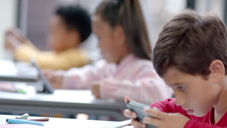 in school, children using tablets and smartphones in classroom, focusing on screens