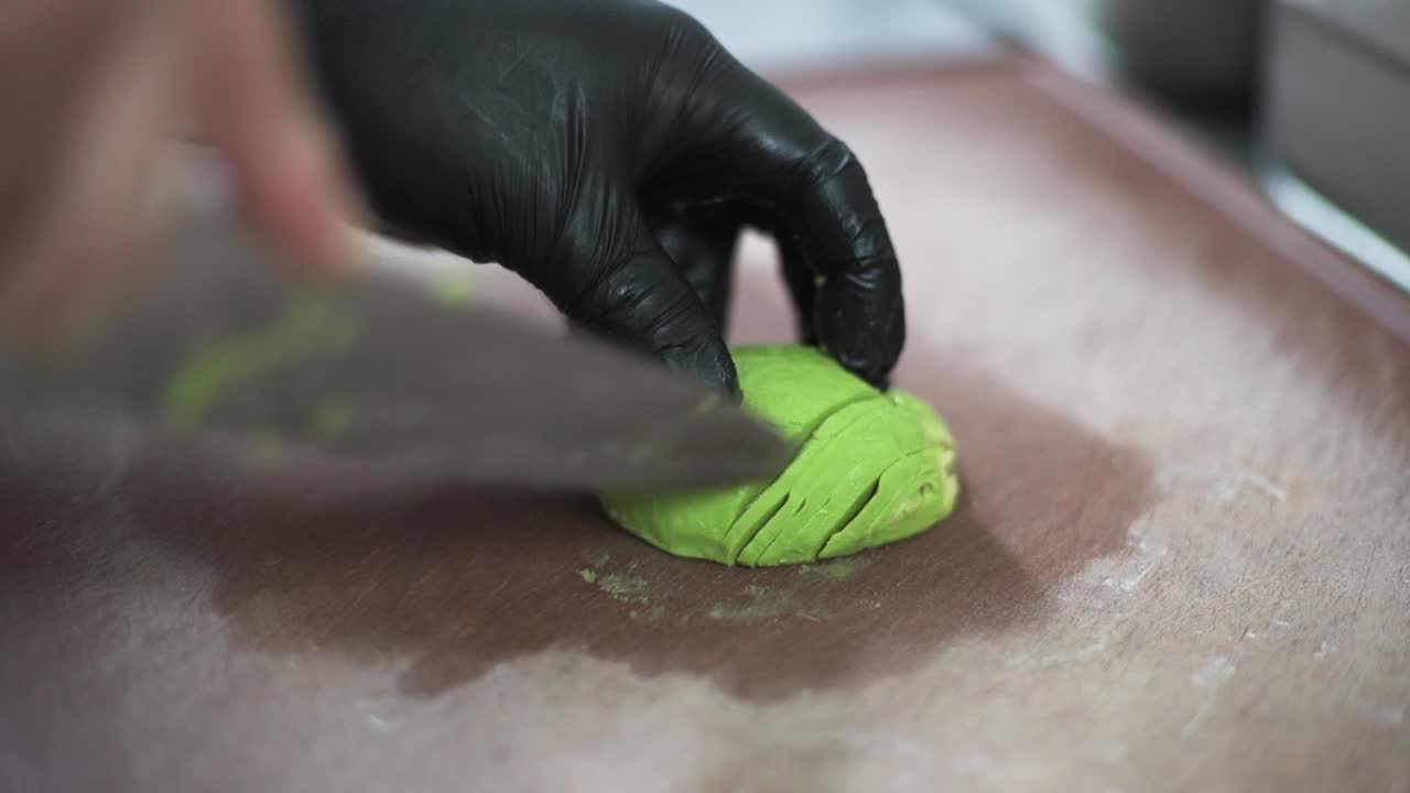Chef hands cutting green avocado on a wooden cutting board, close up