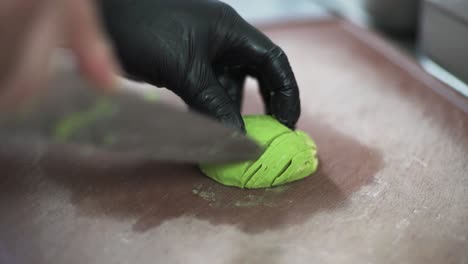 chef hands cutting green avocado on a wooden cutting board, close up