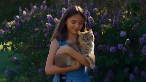 a young girl holding and showing affection to her cat in a garden