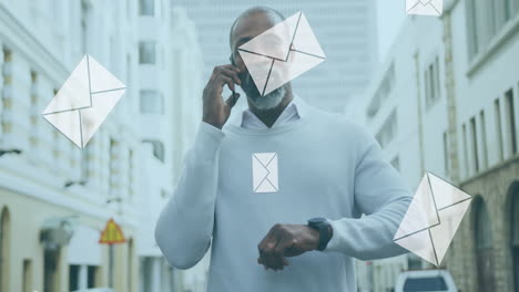 animation of digital mail envelope icons over african american man using smartphone in city