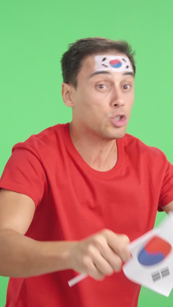 Man cheering for South Korea waving a national flag looking away