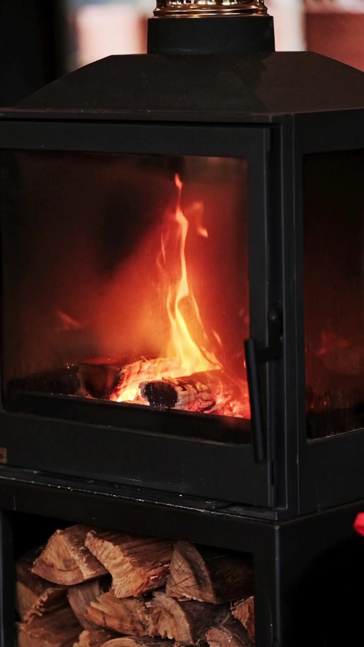 Vertical closeup shot of a cozy wood burner stove with a fire burning