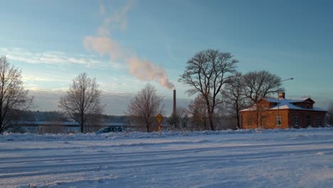 Weißer-Rauch,-Der-In-Einem-Kalten,-Sonnigen-Winter-Aus-Einem-Hohen-Schornstein-Kommt,-Während-Autos-Vorbeifahren