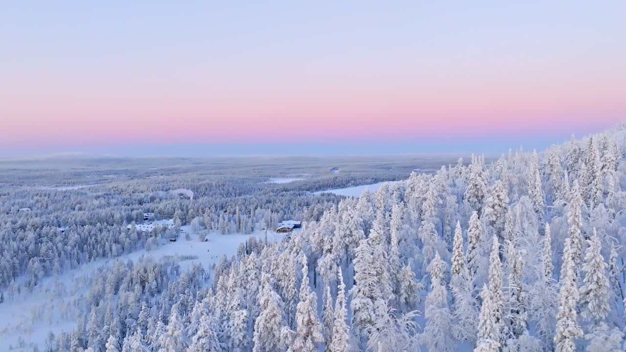 Aerial tracking shot of snowy forest and the Salla ski center, polar night in Finland