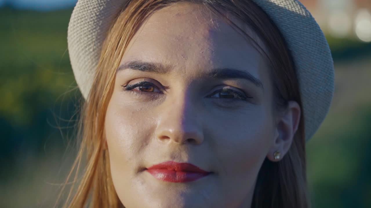 Closeup portrait of smiling young woman wearing hat, looking at camera in soft natural light, capturing relaxed mood and casual lifestyle outdoors in Slovenia