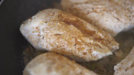 static shot of someone pouring spices on pieces of chicken