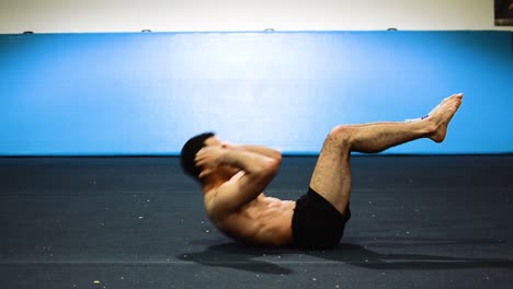 una foto fija de un chico haciendo abdominales en un gimnasio de gimnasia