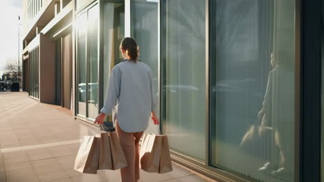 woman walking with shopping bags outside a modern building