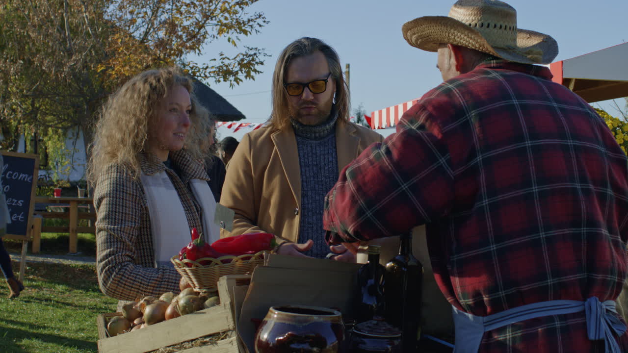 Family Shopping on Local Farmers Market Family Shopping on Local Farmers Market Holder of Sales Point Offers own Product and Gives Eco Bag with Fruits or Vegetables Wife Pays for Purchase by Cash