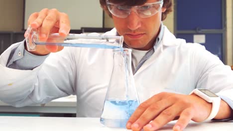 scientist pouring test tube liquid into a erlenmeyer flask