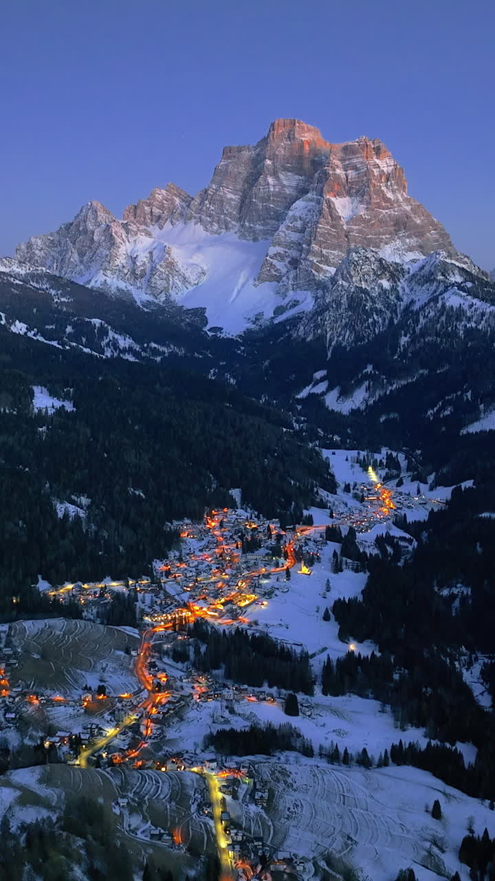 Aerial drone view of the Selva di Cadore comune illuminated at night in the province of Belluno, Dolomites, Italy. Vertical