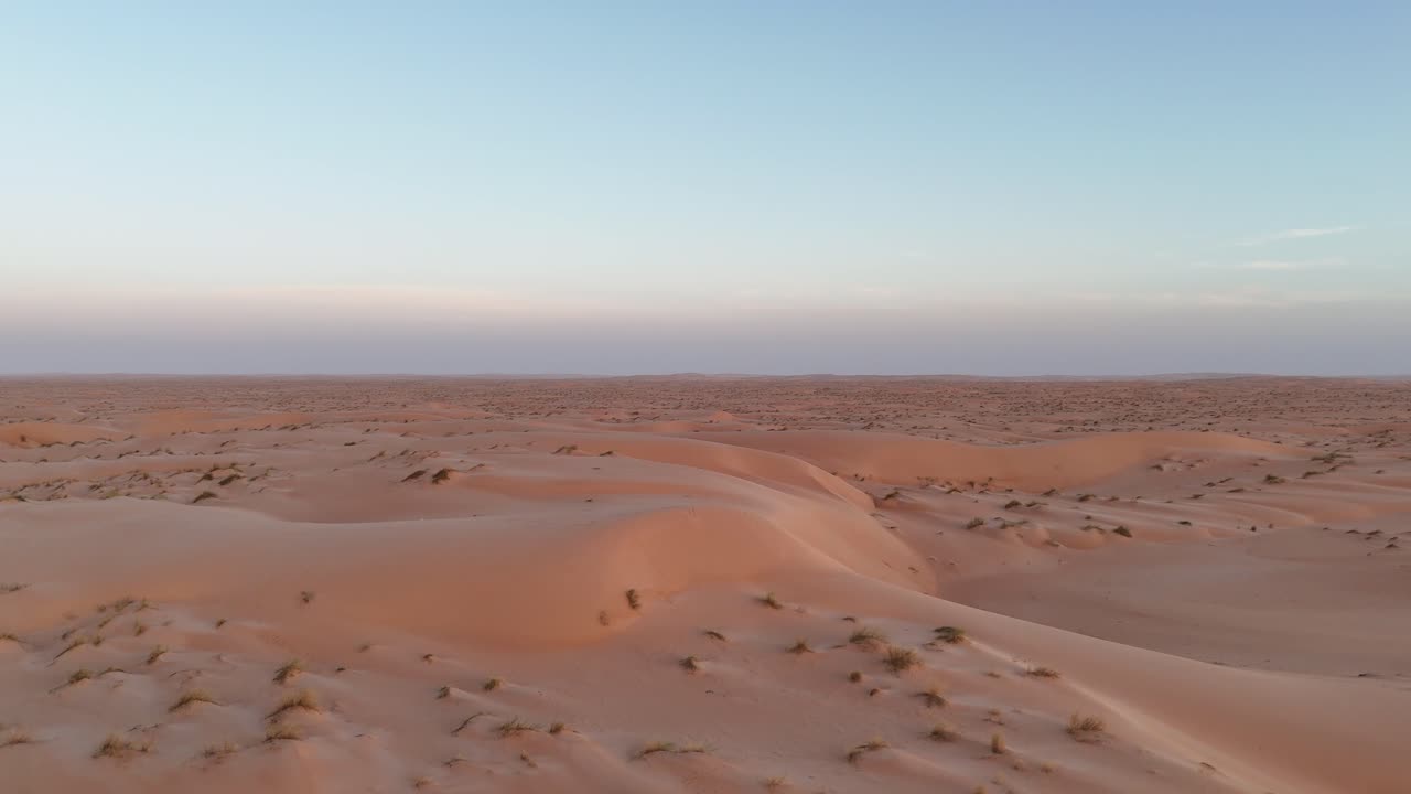 Aerial drone view of sandy desert with sparse vegetation in Mauritania, Sahara wilderness landscape showing dunes, at sunset