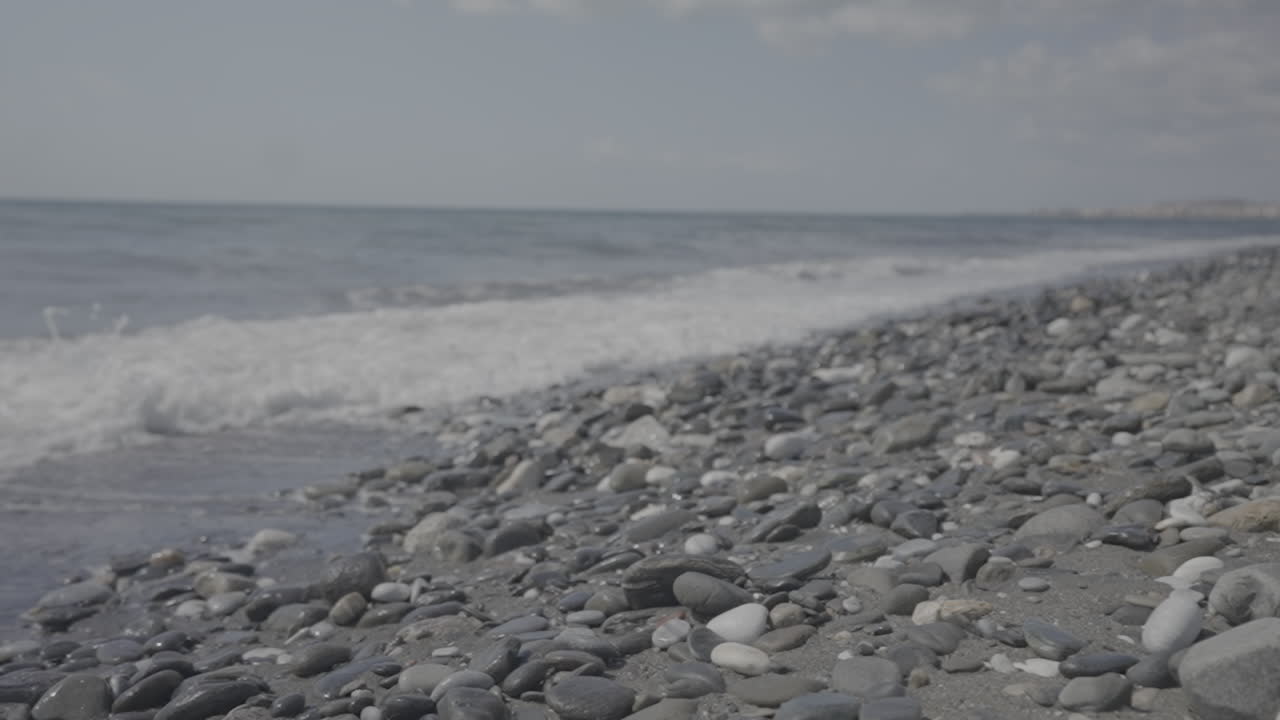 Waves crashing into rocky beach on a sunny day in slowmotion LOG