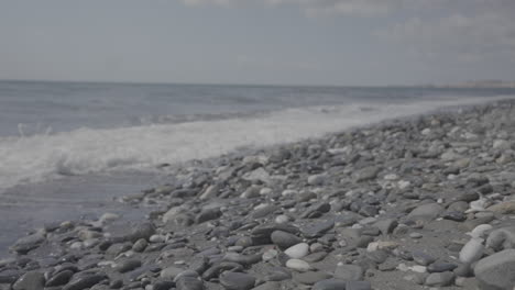 waves crashing into rocky beach on a sunny day in slowmotion log