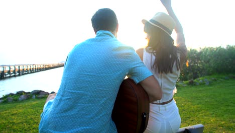 multi ethnic couple playing guitar on beach holiday