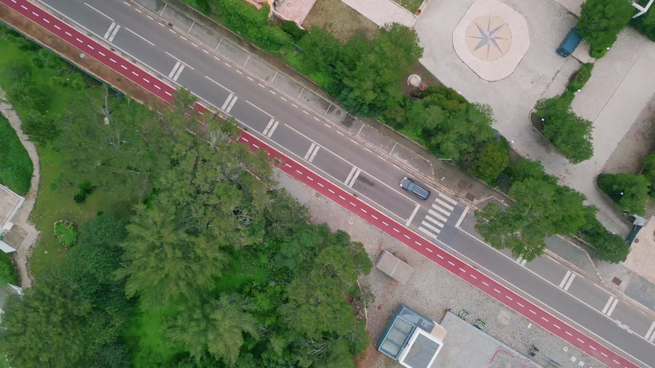 Aerial city road intersecting vivid greenery. Top trees and bushes line street
