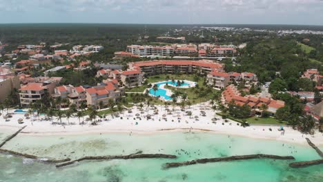 tilt aerial shot revealing turquoise sea transitioning to tropical beachfront resorts and dense greenery in puerto aventuras