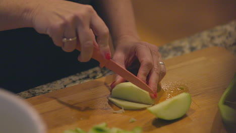 a woman slices a green apple into thin slices in slow motion