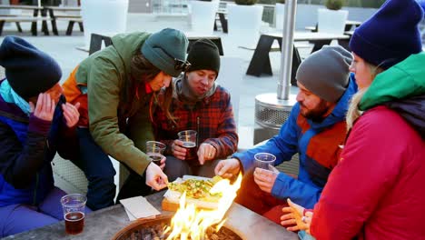 amigos comiendo bocadillos cerca del fuego de campamento