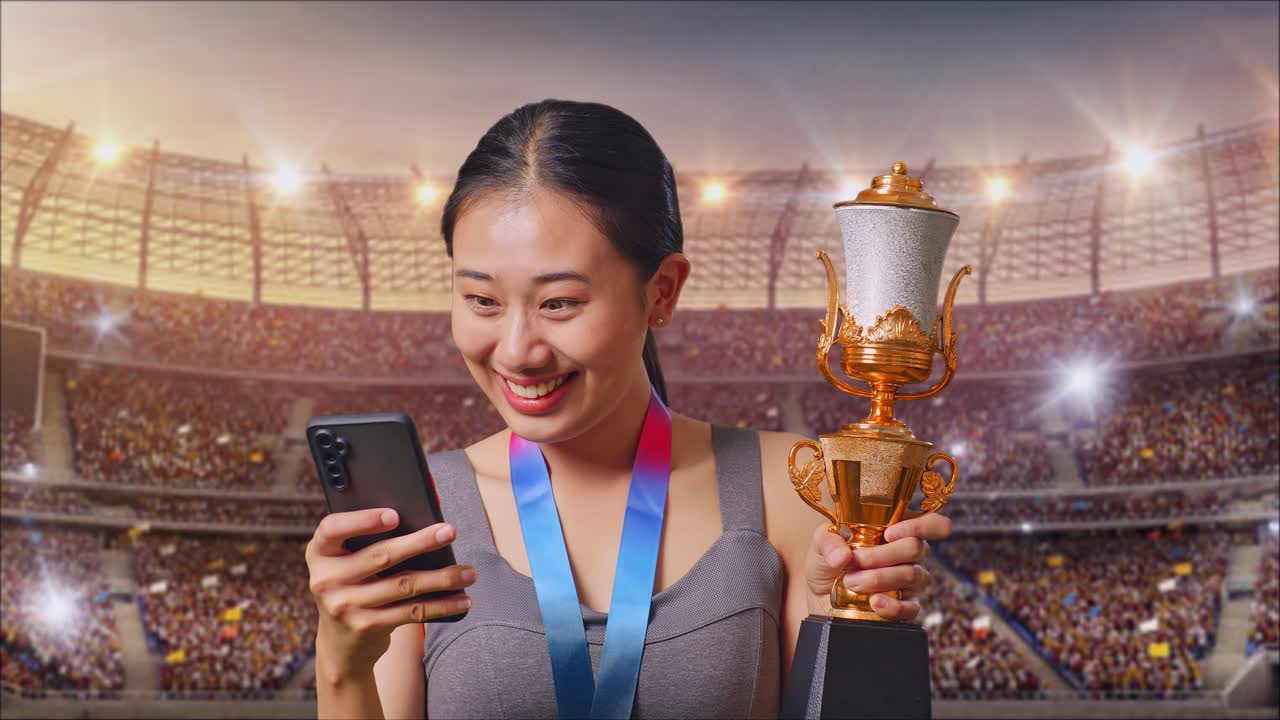 Close Up Of Asian Woman With A Gold Medal And Trophy Looking At Smartphone Then Screaming Goal Celebrating At The Stadium
