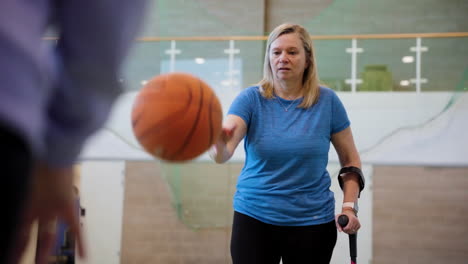 woman using crutches while dribbling a basketball around opponent