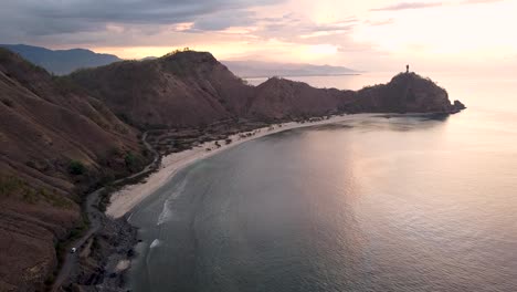 Rising-over-stunning-white-sandy-back-beach,-hilly-terrain-and-the-famous-Cristo-Rei-Jesus-Christ-statue-in-the-capital-Dili,-Timor-Leste,-Southeast-Asia