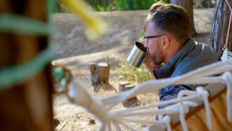 hombre tomando café mientras se relaja en una hamaca 4k