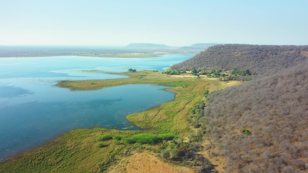 Tomada aérea de drone de colinas arborizadas ao longo de um reservatório em Tighra Gwalior, em Madhya Pradesh, Índia.