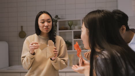 tres amigos japoneses sentados alrededor del mostrador de la cocina y comiendo comida japonesa