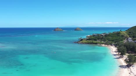 drone flying over the tropical blue water of oahu hawaii towards the mokes island of lanikai