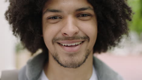 retrato en primer plano de un joven estudiante de raza mixta hombre riendo feliz mirando a la cámara disfrutando de un estilo de vida independiente en la ciudad urbana peinado afro de moda