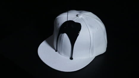 Sombrero-Snapback-Blanco-Cubierto-De-Pintura-Negra-Goteante-Con-Fondo-Negro-Infinito