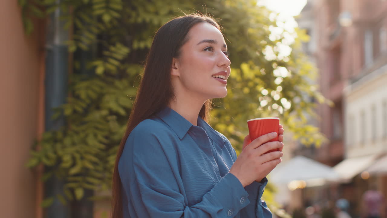 Young woman enjoying drinking morning aroma coffee hot drink relaxing taking a break in city street